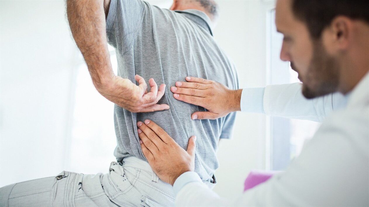 a doctor examines the back with lumbar osteochondrosis